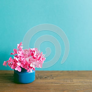Vase of pink hydrangea flowers on wooden table. mint blue wall background