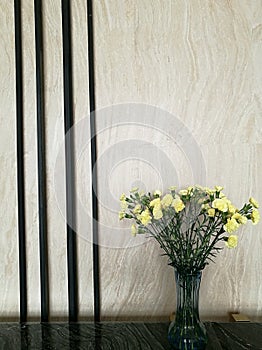 Vase of yellow carnation flower in the right side of marble bar in the hotel lobby with blur background, hotel decoration