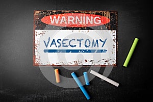 VASECTOMY. Metal warning sign and colored pieces of chalk on a dark chalkboard background