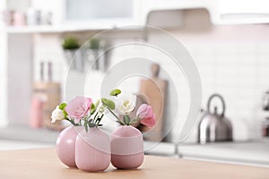 Vases with beautiful flowers on table in kitchen interior.