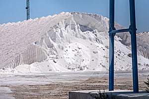Vast mounds of salt dominate the scene, with industrial frames hinting at the scale of this mining operation under a