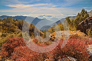 Vast mountain landscape with red vegetation and boulders