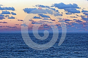 Vast ocean landscape and Cumulus clouds by misty sunset sky