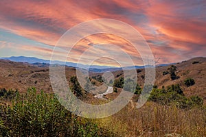 Vast open mountain range landscape covered with dry brush and green trees with blue sky at Chino Hills State Park