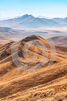 A vast, serene landscape of rolling brown hills and mountains