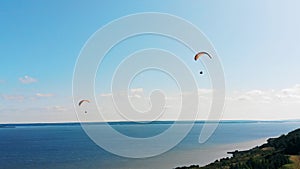 Vast waterscape with people flying around on paraplanes