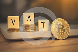 VAT with cryptocurrency bitcoin concept business background. Modern taxes with crypto coin. Desk with laptop, VAT word