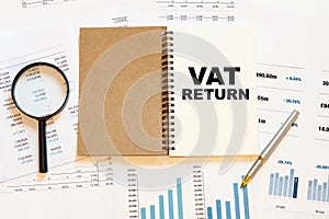 VAT RETURN - financial text on the first page of a notebook, against a background of numbers and charts photo