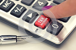 VAT or tax return concept with hand calculator buttons and finger pressing keyboard