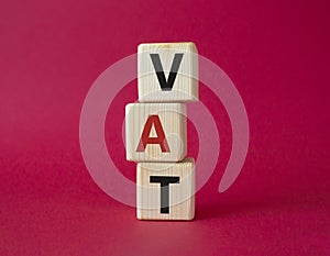 VAT - Value Added Tax symbol. Wooden cubes with word VAT. Beautiful red background. Business and Value Added Tax concept. Copy