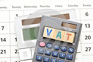 VAT word arranged with wooden letters on the calculator screen. Settlement VAT in Poland