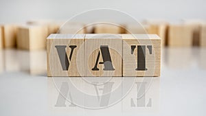 VAT word is made of wooden building blocks lying on the gray table, concept