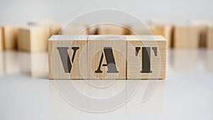 VAT word is made of wooden building blocks lying on the gray table, concept.