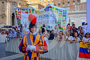 A portrait of a swiss guard in Vatican city, crowd of people in the main square waiting for the holy mass on sunday with Pope