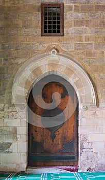 Vaulted closed decorated wooden grunge door in bricks stone wall