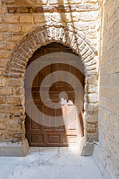Vaulted closed wooden grunge door in bricks stone wall