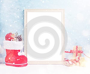 VBright christmas mock up with large photo frame: festive gift boxes, toys, and fir-cones in red santa`s boot under snow