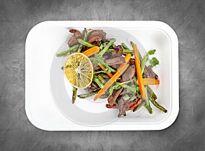 Veal with beans and orange. Healthly food. Takeaway food. Top view, on a gray background