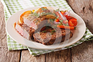 Veal breaded rump steak and garnished with vegetables close-up.