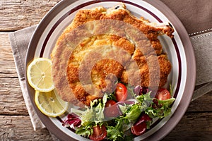 Veal milanese cotoletta alla milanese with lemon and fresh veg photo