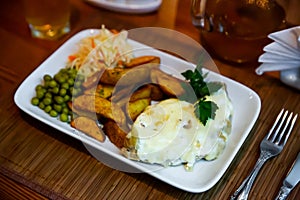 Veal Orloff with potato wedges, green peas and cabbage salad