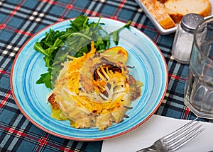 Veal Orloff served on baked potato with fresh arugula