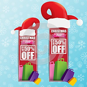 Vector Christmas sales paper banner or tag label with red santa hat on snowy blue background with falling snowflakes