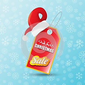 Vector Christmas sales paper banner or tag label with red santa hat on snowy blue background with falling snowflakes