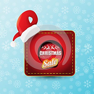 Vector Christmas sales paper banner or tag label with red santa hat on snowy blue background with falling snowflakes