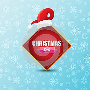 Vector Christmas sales paper banner or tag label with red santa hat on snowy blue background with falling snowflakes