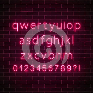 Vector neon style font. Glowing red neon alphabet with lowercase letters on dark brick wall background.