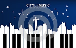 Vector silhouette of conductor with piano key shaped the the big city outline silhouette.