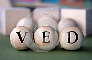 VED - acronym on wooden balls on the background of wooden large cubes