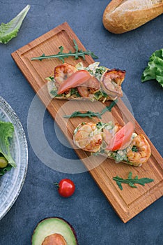 Vediterranean vegetable salad of fresh tomato, olives, capers, onion, spinach, lettuce and sesame on plate. Grillled shrimp