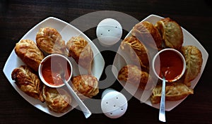 Veg fried cheese momos with sauce in white plates on a wooden table