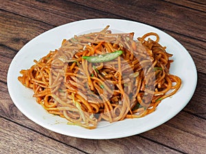 Veg Noodles a popular indo-chinese dish made with noodles and vegetables, served over a rustic wooden background, selective focus