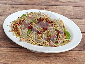 Veg Noodles a popular indo-chinese dish made with noodles and vegetables, served over a rustic wooden background, selective focus