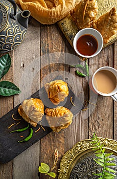 veg samosa with sauce and tea served in a dish isolated on dark background top view food