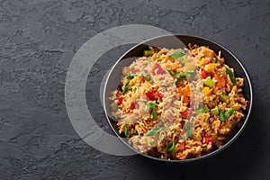 Veg Schezwan Fried Rice in black bowl at dark slate background. indo-chinese cuisine dish