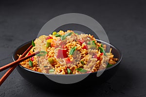 Veg Schezwan Fried Rice in black bowl at dark slate background. indo-chinese cuisine dish