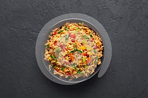 Veg Schezwan Fried Rice in black bowl at dark slate background. indo-chinese cuisine dish