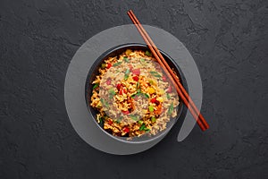 Veg Schezwan Fried Rice in black bowl at dark slate background. indo-chinese cuisine dish