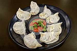 Veg steamed momo. Nepalese Traditional dish Momo stuffed with vegetables and then cooked and served with sauce on a ceramic black