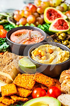 Vegan appetizer platter. Hummus, tofu, vegetables, fruits and bread on black tray