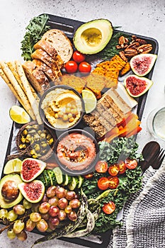 Vegan appetizer platter. Hummus, tofu, vegetables, fruits and bread on black tray