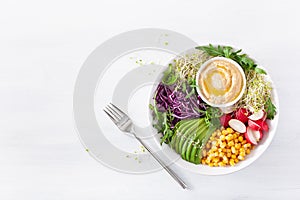 Vegan avocado sweet corn lunch bowl with hummus, red cabbage, radish and sprouts