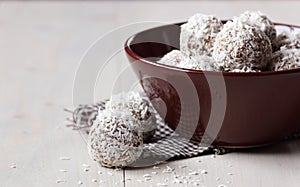 Vegan balls with dates, peanut butter and coconut on dark moody background