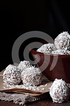 Vegan balls with dates, peanut butter and coconut on dark moody background