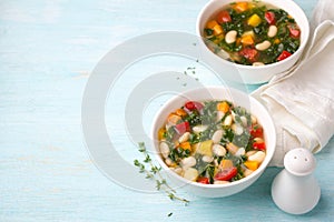 Vegan bean soup with vegetables and kale cabbage in white bowls on blue background