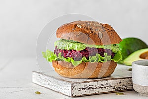Vegan beetroot burger with avocado sauce and lettuce salad on black background. Healthy vegetarian food